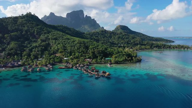 Bora Bora aerial drone video of travel vacation paradise with overwater bungalows luxury resort, coral reef lagoon ocean beach. Mount Otemanu, Bora Bora, French Polynesia, Tahiti, South Pacific Ocean