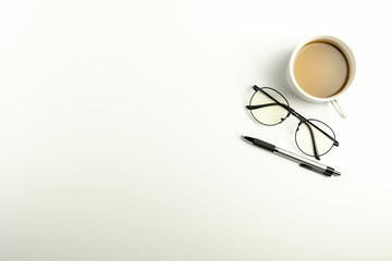 White office desk with glasses, pen and a coffee cup. - Top view with copy space.