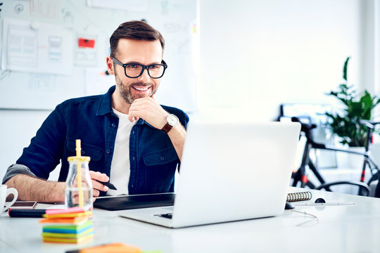 Casual businessman working on laptop at desk in office