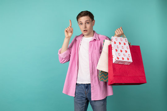 Young handsome man standing thoughtfully with shoping bags in hand