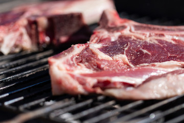 Raw steaks on barbecue close up.