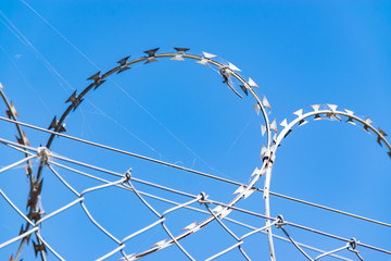 Barbed wire of a fence against blue sky