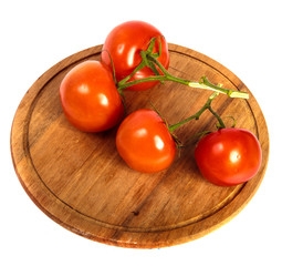 ripe red tomatoes on a round wooden cutting board. white background