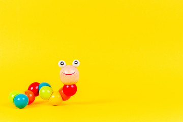Fototapeta na wymiar Colorful wooden baby toy worm on yellow background