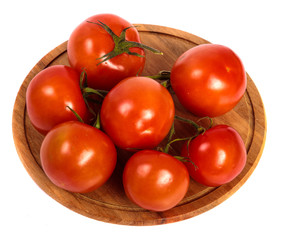 ripe red tomatoes on a round wooden cutting board. white background