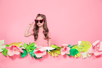 Portrait of a little girl with sunglasses on a pink background
