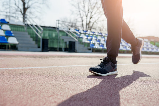 Photo from side of legs of athlete running through stadium