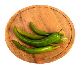 Green chilli peppers on a wooden cutting board. on a white background