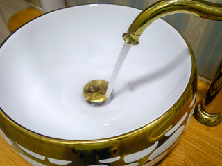 gold color sink and running faucet