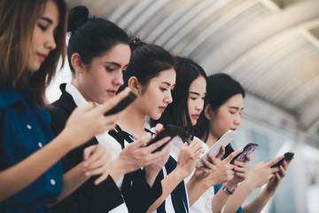 attractive asian businesswomen team playing smartphone outdoor city background