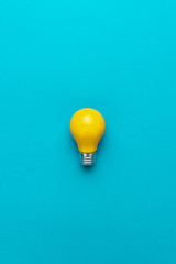 flat lay minimalist photo of yellow painted bulb on turquoise blue backgound