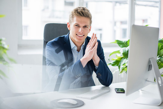 Portrait of confident young businessman sitting at desk in office