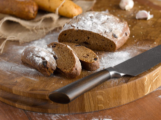 Closeup of a beautiful cutting board and a knife with a cut bread baguette
