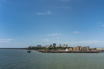 Fototapeta premium Darwin Australia - February 22, 2019: western side of Darwin skyline seen from south upon harbour bay water under blue sky. Convention center to the left. Dock for larger ships up front. 