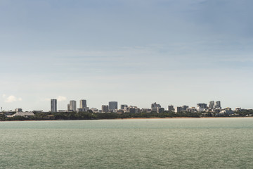 Darwin Australia - February 22, 2019: Darwin skyline seen from East Point over Fannie Bay sea water under light cloudy sky.