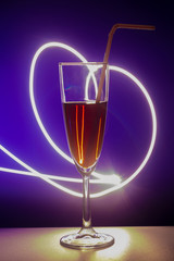 glass of cocktail with background. A glass on the bar in a cafe, restaurant, nightclub or disco. Glass or stemware with alcohol or a cocktail on a colored background.
