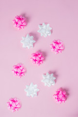 Pink and white ribbon bow on pink background. Greeting card with copy space. Vertical image.Holiday decorations. Creative flat lay.