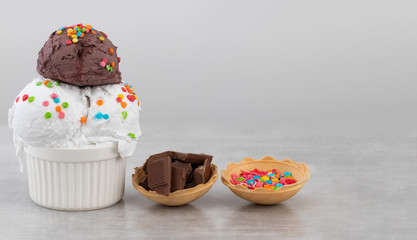 plate of vanilla and chocolate ice cream scoops swith sprinkles chocolate pieces and waffle cones