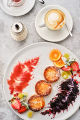 Cottage cheese pancakes, syrniki, curd fritters with fresh berries, grapes and orange.