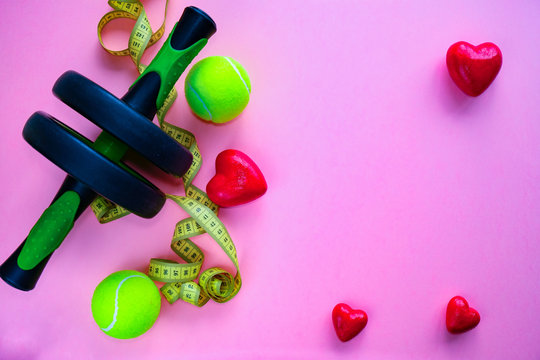 Sports items and figures of hearts lie on a pink background. Love of sport
