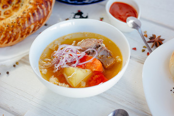 Uzbek chorba - soup from fresh meat and vegetables on white table.