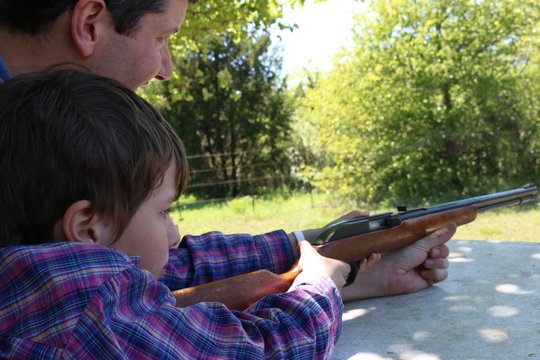 Father teaching his child to shoot a gun