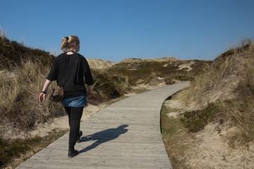 Frau geht auf einem schönen Pfad durch malerische Dünen Landschaft auf Sylt