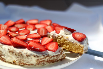 Gluten free almond sponge cake decorated with whip cream and strawberries. Selective focus.