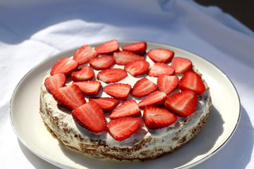Gluten free almond sponge cake decorated with whip cream and strawberries. Selective focus.