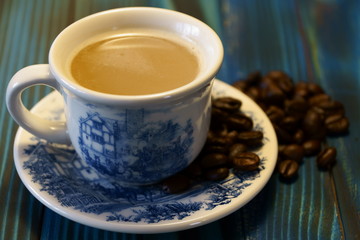 cup of coffee with beans on wooden table