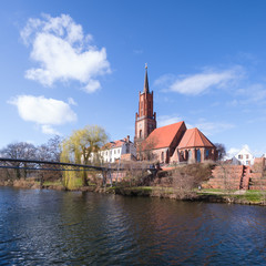 Sankt-Marien-Andreas-Kirche im alten Hafen der Stadt Rathenow im Havelland vor blauem Himmel mit Wolken	