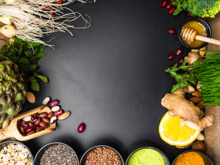 Super food or vegetarian food concept. Seeds, beans, vegetables, wheat seedlings, honey, citrus for healthy cooking on black wooden background
