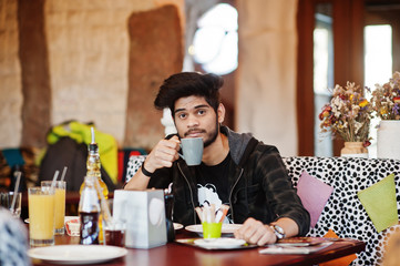 Beard asian man in casual wear sitting indoor cafe and drink coffee.