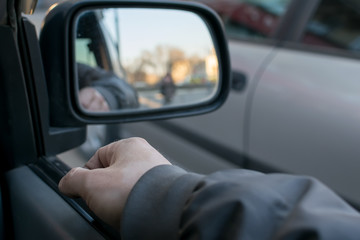 a man's hand on the car door on the background of a female silhouette in the mirror of the rear view mirror