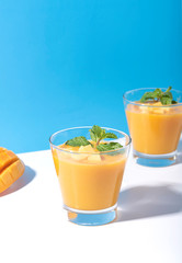 Fresh mango smoothie and ripe mango slice on color background. summer drink.
