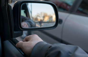 Fototapeta na wymiar a man's hand on the car door on the background of a female silhouette in the mirror of the rear view mirror