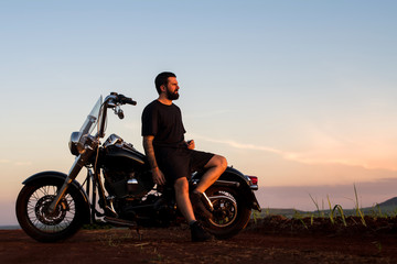 Fototapeta na wymiar Young man sitting on his custom classic motorcycle admiring the landscape