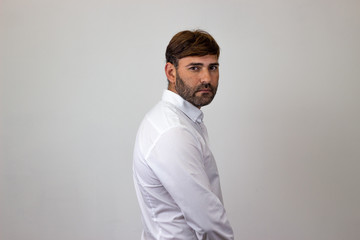 Obraz premium Fashion portrait of handsome young man with brown hair looking sad, their back facing the camera and looking at the camera. Isolated on white background.