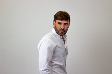 Obraz premium Moda portret przystojny młodzieniec z brązowymi włosami z nienawiści, ich plecami twarzą do aparatu i patrząc w kamerę. Na białym tle
