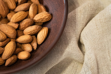 Almonds in a brown bowl on the background of linen