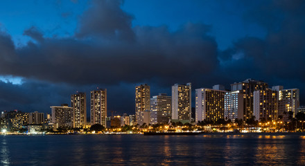 Fototapeta na wymiar Waikiki Beach at night with dramatic dark clouds in the sky