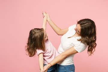Woman in light clothes have fun with cute child baby girl. Mother, little kid daughter isolated on pastel pink wall background, studio portrait. Mother's Day, love family, parenthood childhood concept