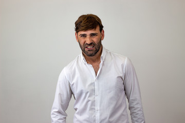 Obraz premium Moda piękny portret przystojny młody człowiek z brązowymi włosami, patrząc zniesmaczony, patrząc w kamerę. Na białym tle