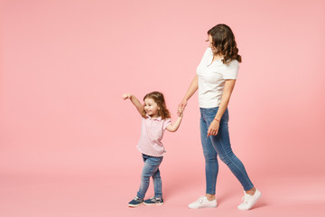 Woman in light clothes have fun with cute child baby girl. Mother, little kid daughter isolated on pastel pink wall background, studio portrait. Mother's Day, love family, parenthood childhood concept