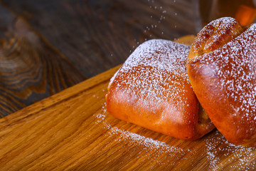 Sweet bun with poppy seeds on a wooden background.