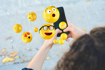 Woman using smartphone sending emojis.