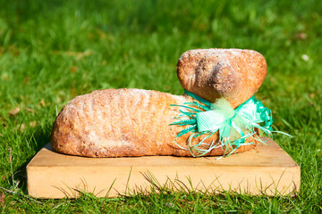 Easter lamb cake on a wooden kitchen cutting board lying on the green grass