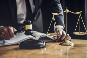 Professional Male lawyer or judge working with contract papers, documents and gavel and Scales of justice on table in courtroom, Law and Legal services concept
