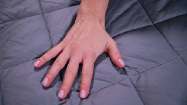 Female hand touching soft and clean grey blanket