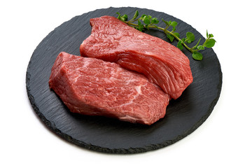 Fresh raw beef steaks on slate shale plate, sliced meat, close-up, isolated on white background